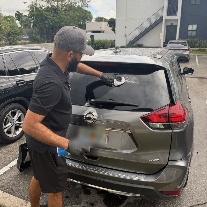 Technician cleaning the new back glass on a Nissan Rogue