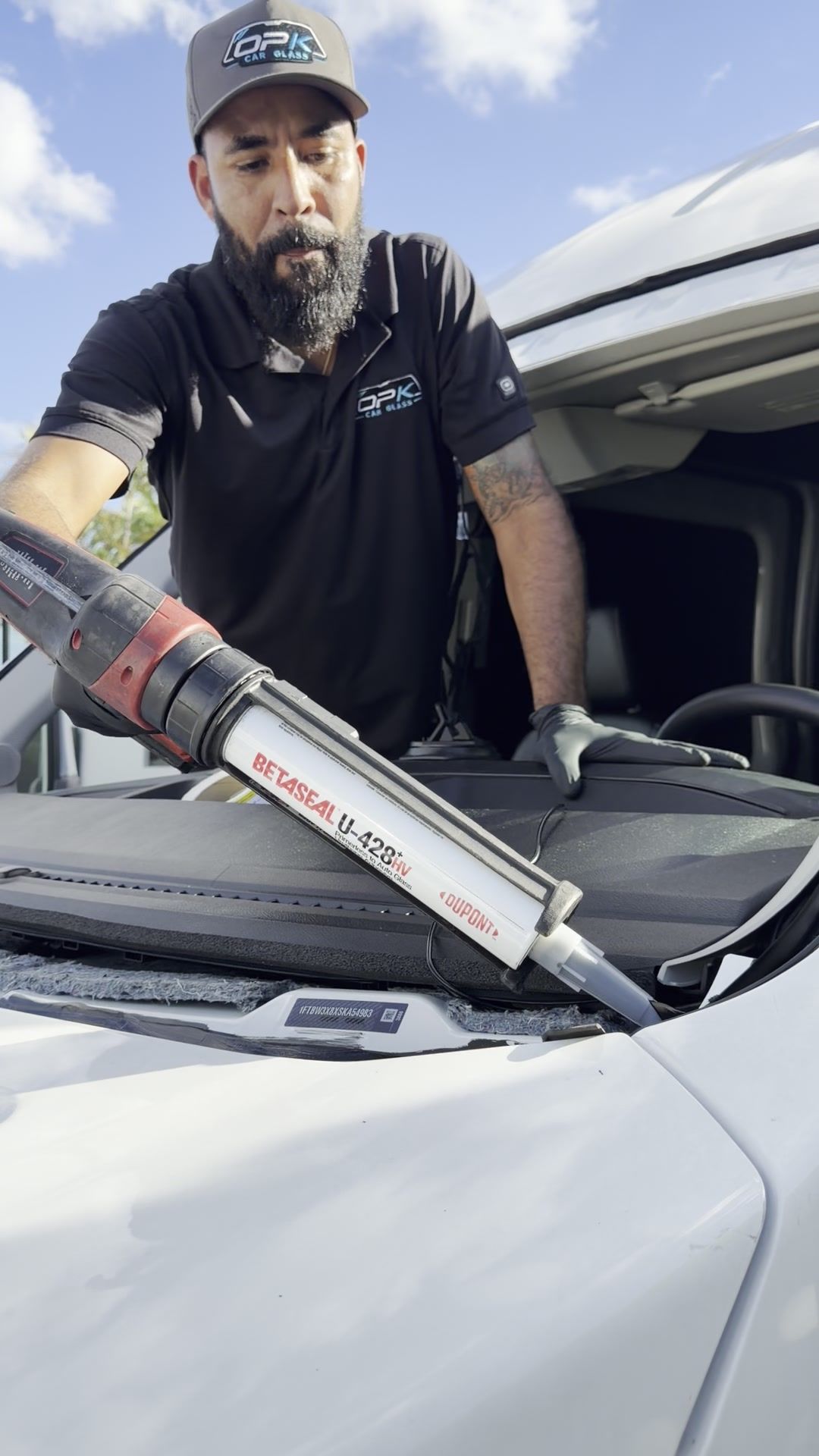Technician laying urethane on the Ford Transit windshield frame